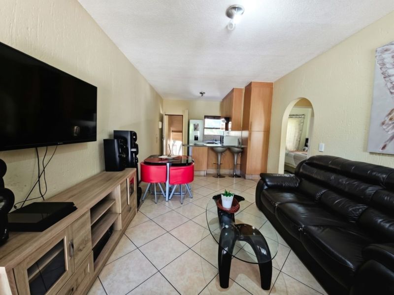 Open-plan living and kitchen area featuring tiled flooring, built-in cabinetry, and an arched transition to the adjacent room.