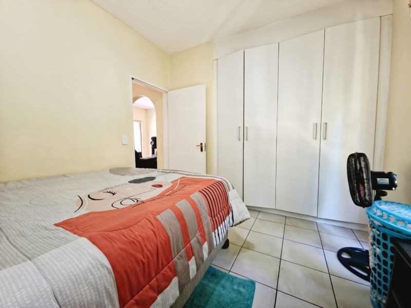 A functional bedroom featuring built-in cupboards and tiled flooring, offering a clean and practical space for rest.