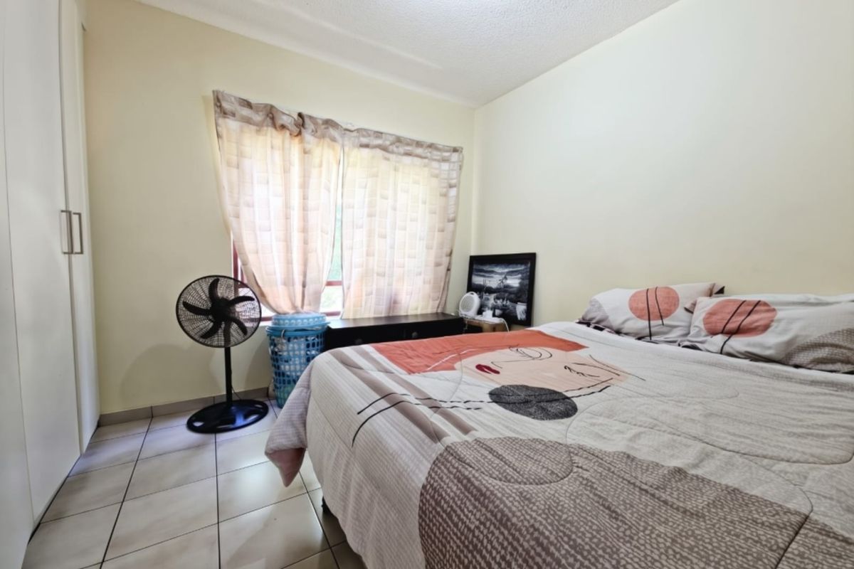 A functional bedroom featuring tiled flooring and a built-in wardrobe, offering a neutral canvas for potential interior updates.