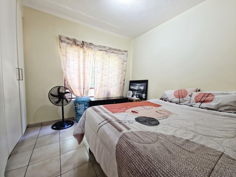 A functional bedroom featuring tiled flooring and a built-in wardrobe, offering a neutral canvas for potential interior updates.