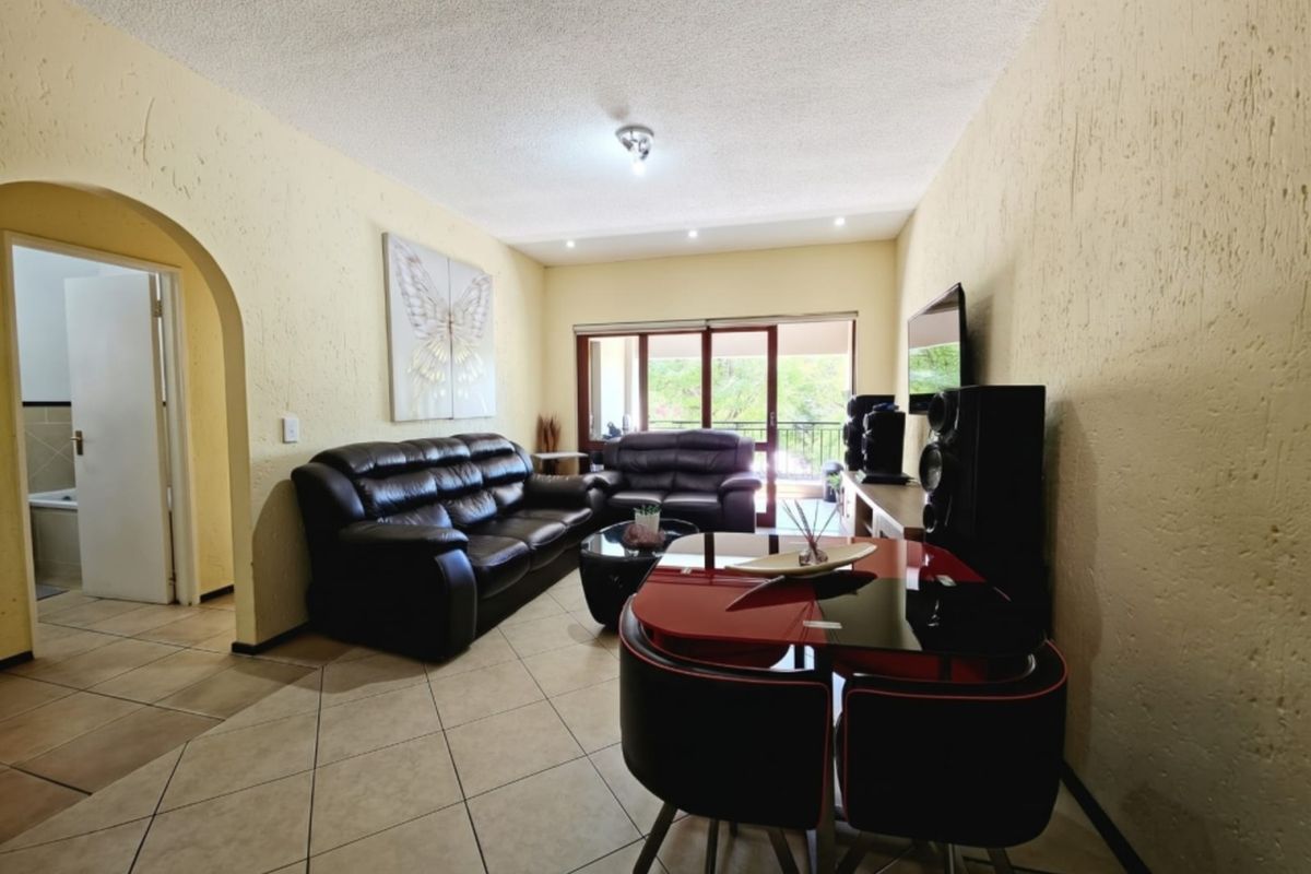 Open-plan living area featuring tiled flooring, textured walls, and a sliding glass door leading to an outdoor balcony.