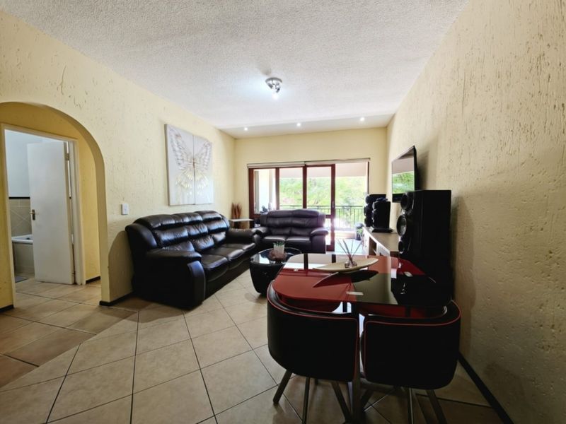 Open-plan living area featuring tiled flooring, textured walls, and a sliding glass door leading to an outdoor balcony.