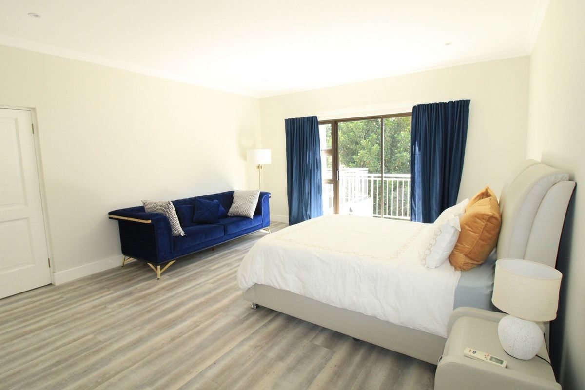 Spacious bedroom featuring modern laminate flooring, recessed lighting, and direct access to a private balcony through sliding glass doors.