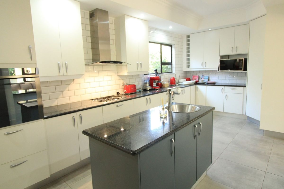 Modern kitchen featuring a central island, granite countertops, subway tile backsplash, built-in appliances, and ample cabinetry storage.