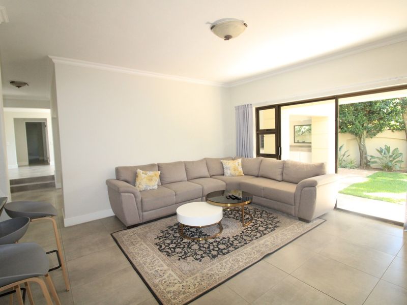 Spacious living room featuring neutral tiled flooring and large sliding glass doors that provide seamless access to the outdoor patio and garden area.
