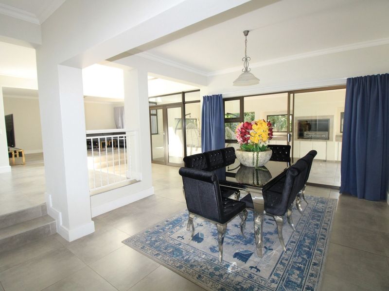Spacious dining area featuring large format floor tiles, coved ceilings, and sliding glass doors leading to an outdoor area with a built-in braai.