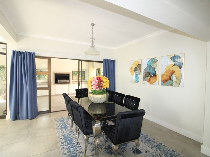 A bright dining room featuring tiled flooring, cove cornicing, and large sliding glass doors that provide seamless access to the outdoor patio area.