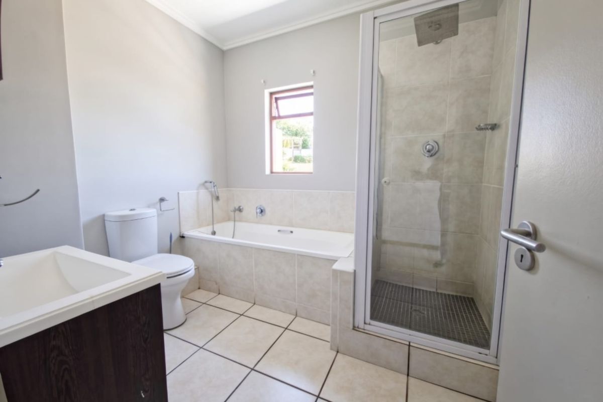 A clean and functional bathroom featuring a built-in vanity, a tiled bathtub, and a separate glass-enclosed shower with neutral finishes.