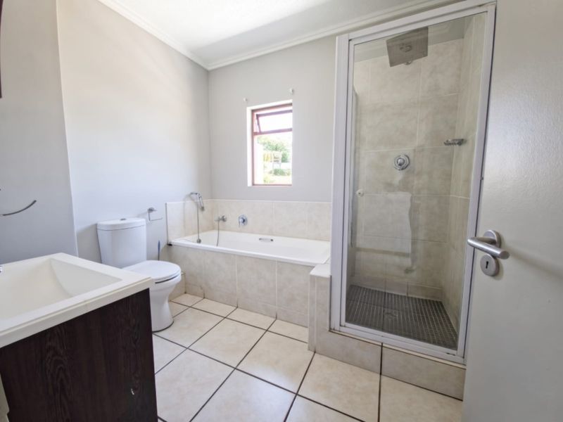 A clean and functional bathroom featuring a built-in vanity, a tiled bathtub, and a separate glass-enclosed shower with neutral finishes.