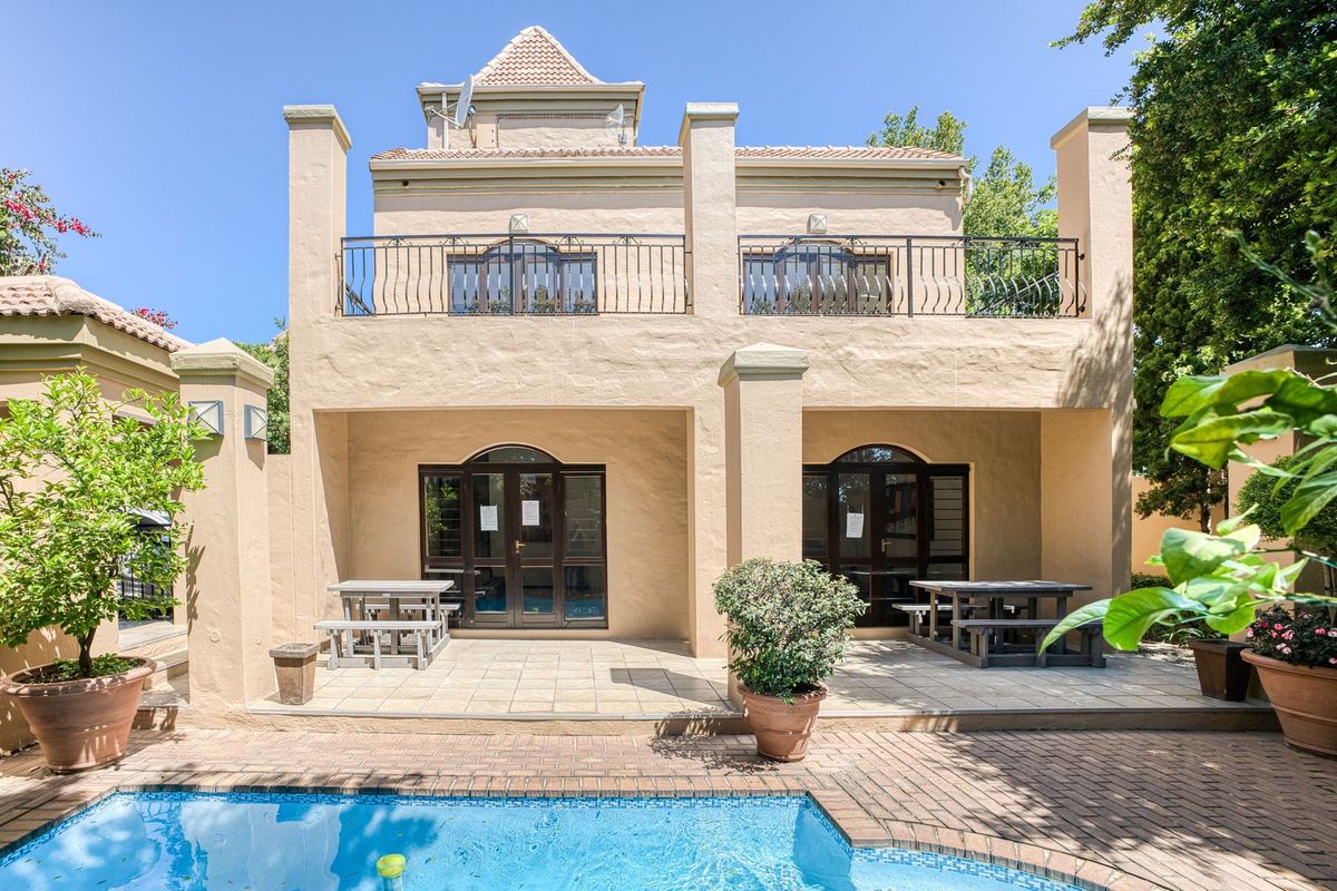 Rear view of the apartment featuring a covered patio, a swimming pool, and a balcony with wrought iron railings.