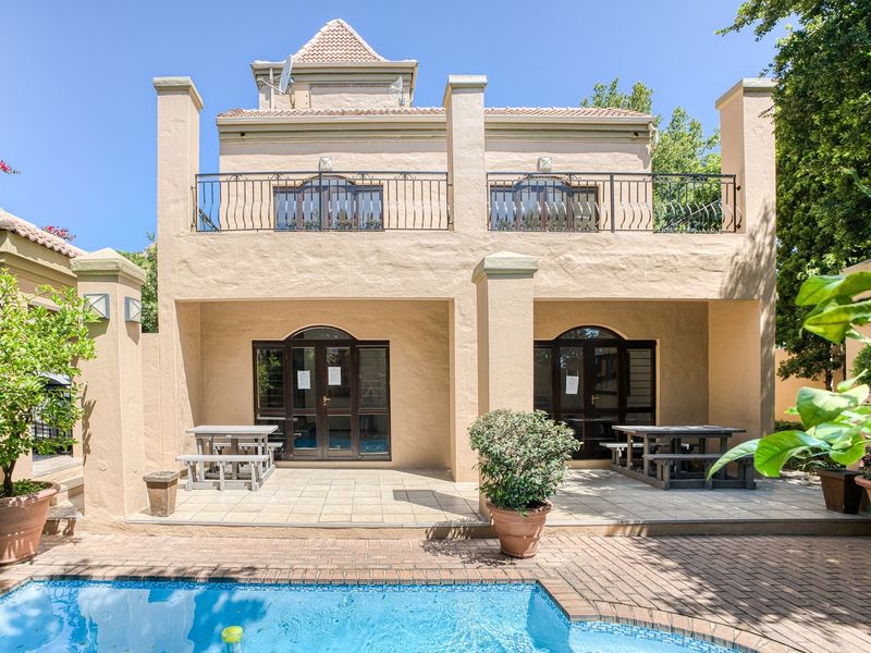 Rear view of the apartment featuring a covered patio, a swimming pool, and a balcony with wrought iron railings.