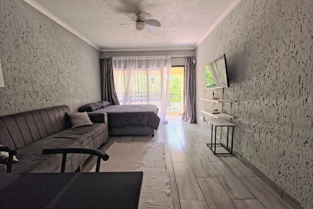 A bedroom featuring textured walls, tiled flooring, a ceiling fan, and direct access to a balcony through sliding glass doors.