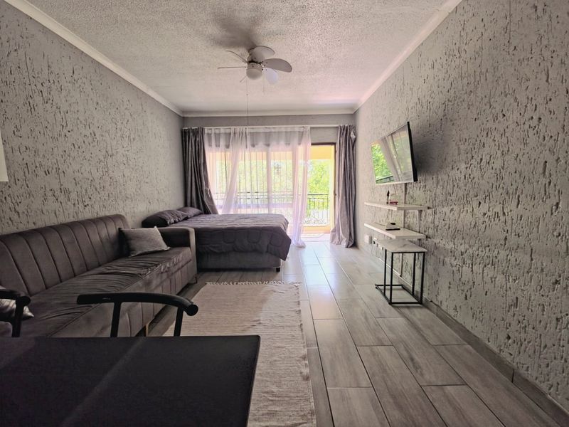 A bedroom featuring textured walls, tiled flooring, a ceiling fan, and direct access to a balcony through sliding glass doors.