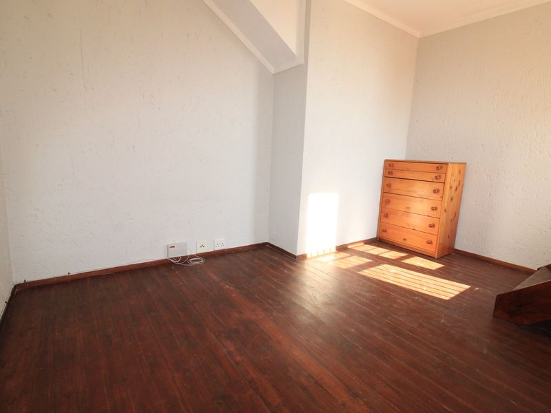 A vacant bedroom featuring dark hardwood flooring and textured walls, offering a blank canvas for personalization.