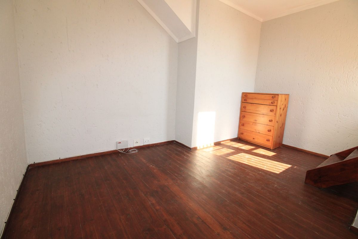 A vacant bedroom featuring dark hardwood flooring and textured walls, offering a blank canvas for personalization.