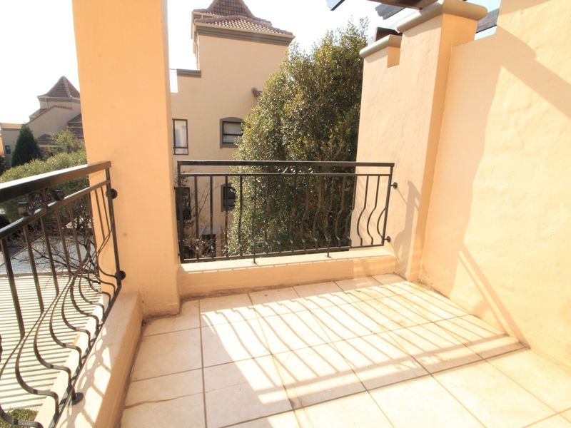 A private balcony featuring tiled flooring and a decorative wrought iron balustrade, offering an open outdoor space for relaxation.