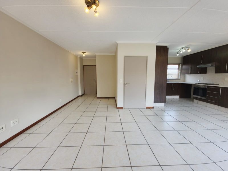 Spacious open-plan living area featuring tiled flooring and a modern kitchen with built-in cabinetry, oven, and hob.