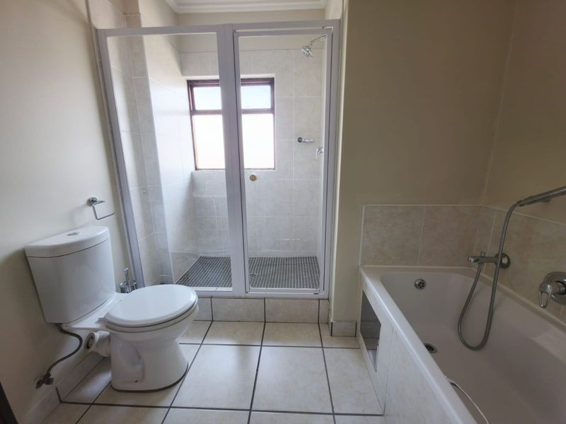 A functional bathroom featuring a separate shower enclosure, built-in bathtub, and tiled flooring, offering a clean and practical layout.
