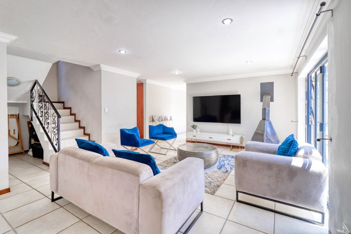 Spacious living room featuring tiled flooring, a modern freestanding fireplace, recessed lighting, and a staircase with a decorative wrought iron balustrade.