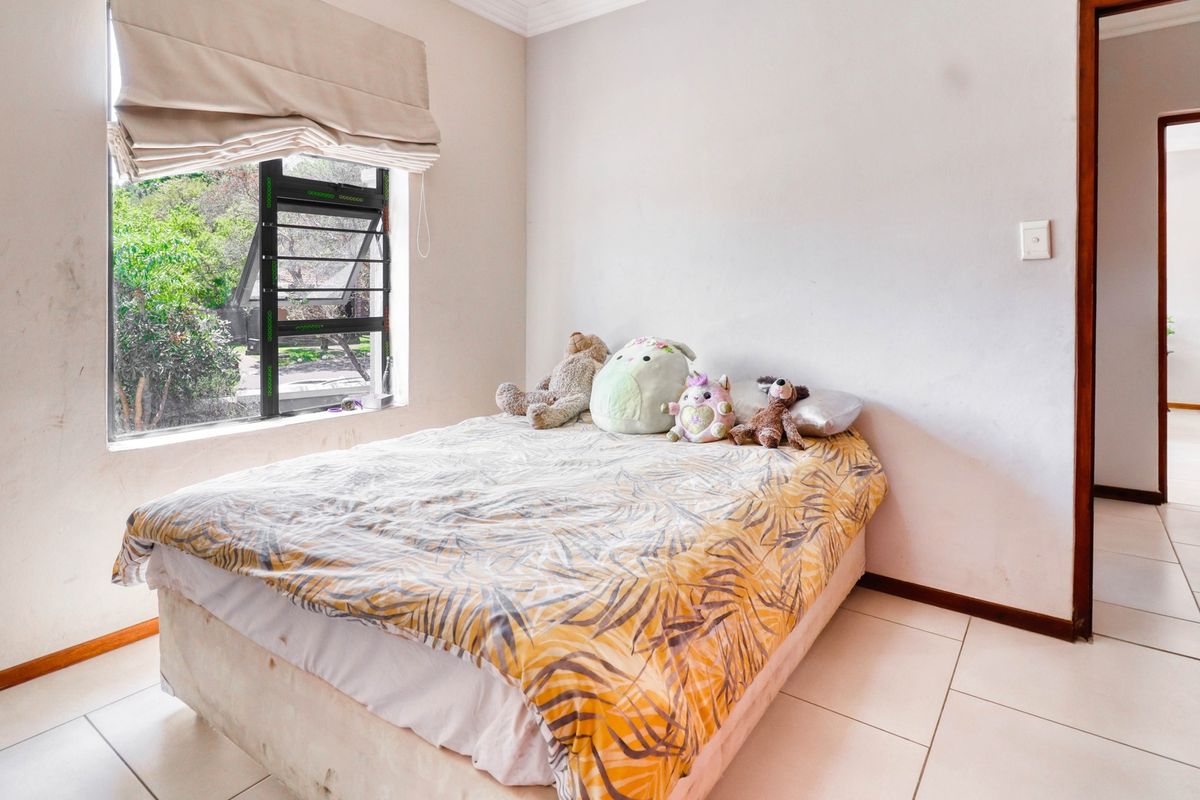 A bedroom featuring tiled flooring, a top-hung window with a roman blind, and neutral wall finishes.