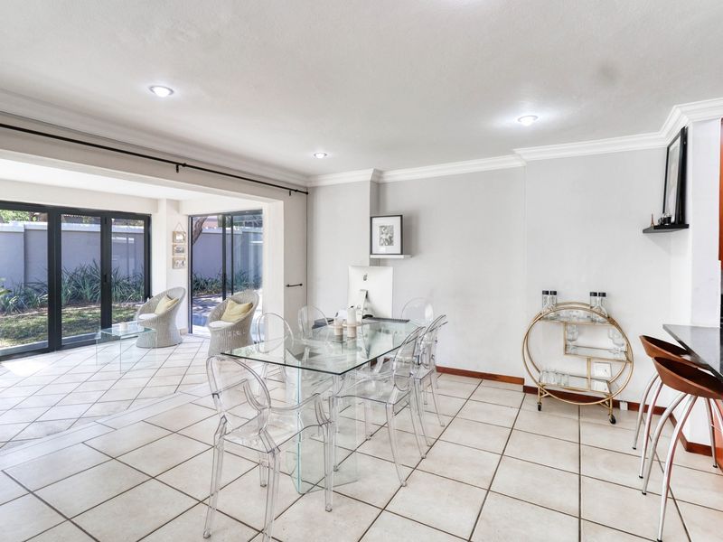 Spacious open-plan living and dining area featuring tiled floors, recessed lighting, and seamless access to the outdoor patio through large sliding glass doors.