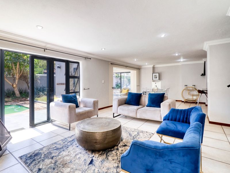 Spacious open-plan living area featuring tiled floors, recessed lighting, and large aluminium sliding doors providing seamless access to the outdoor pool area.