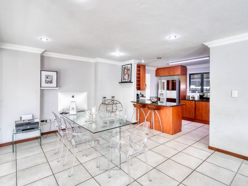 Open-plan living and dining area featuring tiled floors, crown molding, and a functional kitchen with granite countertops and a breakfast bar.