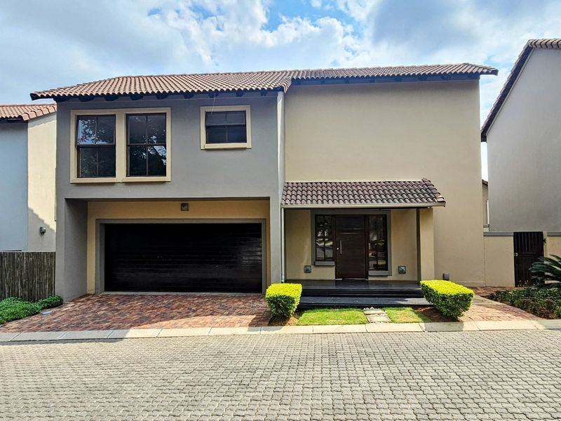 Modern double-story residential home featuring a paved driveway, double garage, and a covered entrance with timber decking.