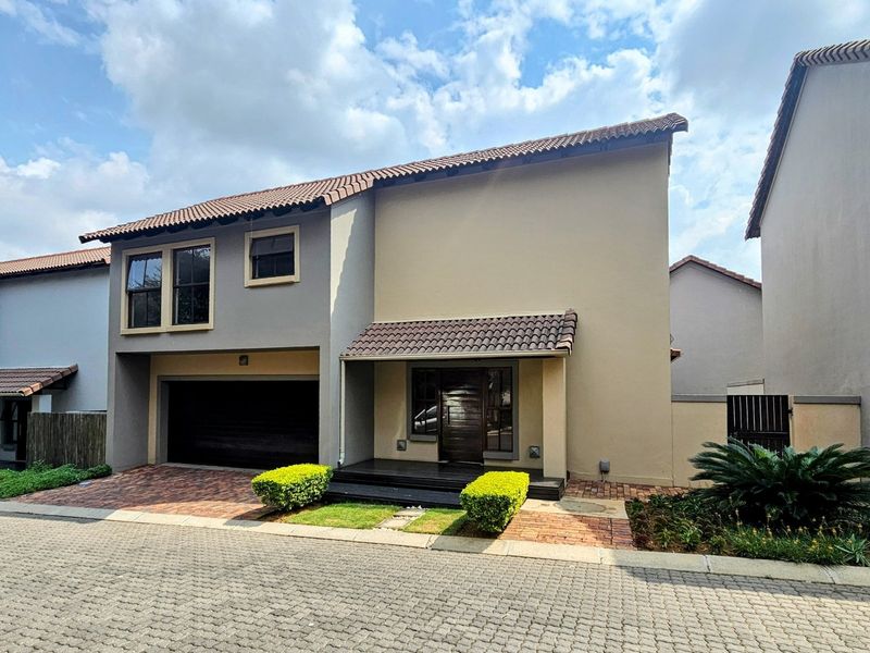 Front elevation of a modern double-storey house featuring a tiled roof, integrated double garage, paved driveway, and a covered entrance with timber decking.