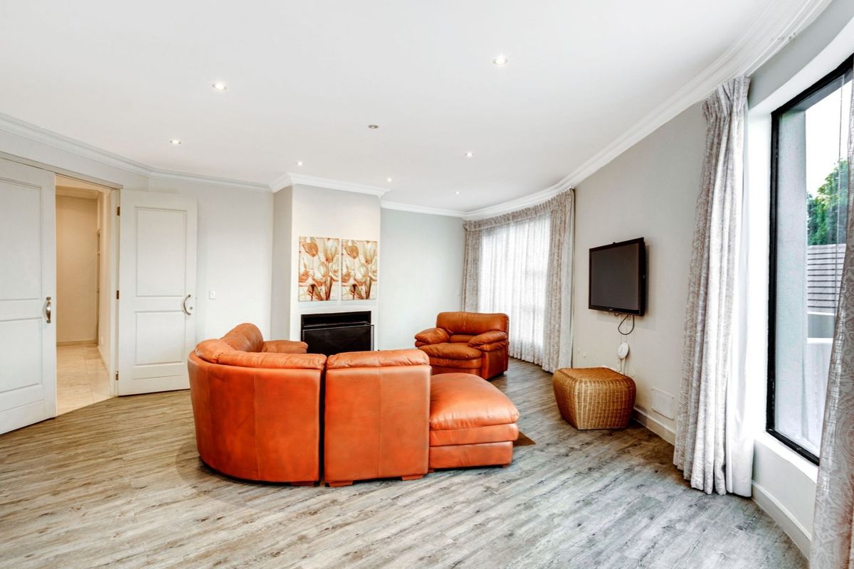 Spacious living room featuring wood-look flooring, recessed ceiling lighting, a built-in fireplace, and large windows with curtain tracks.