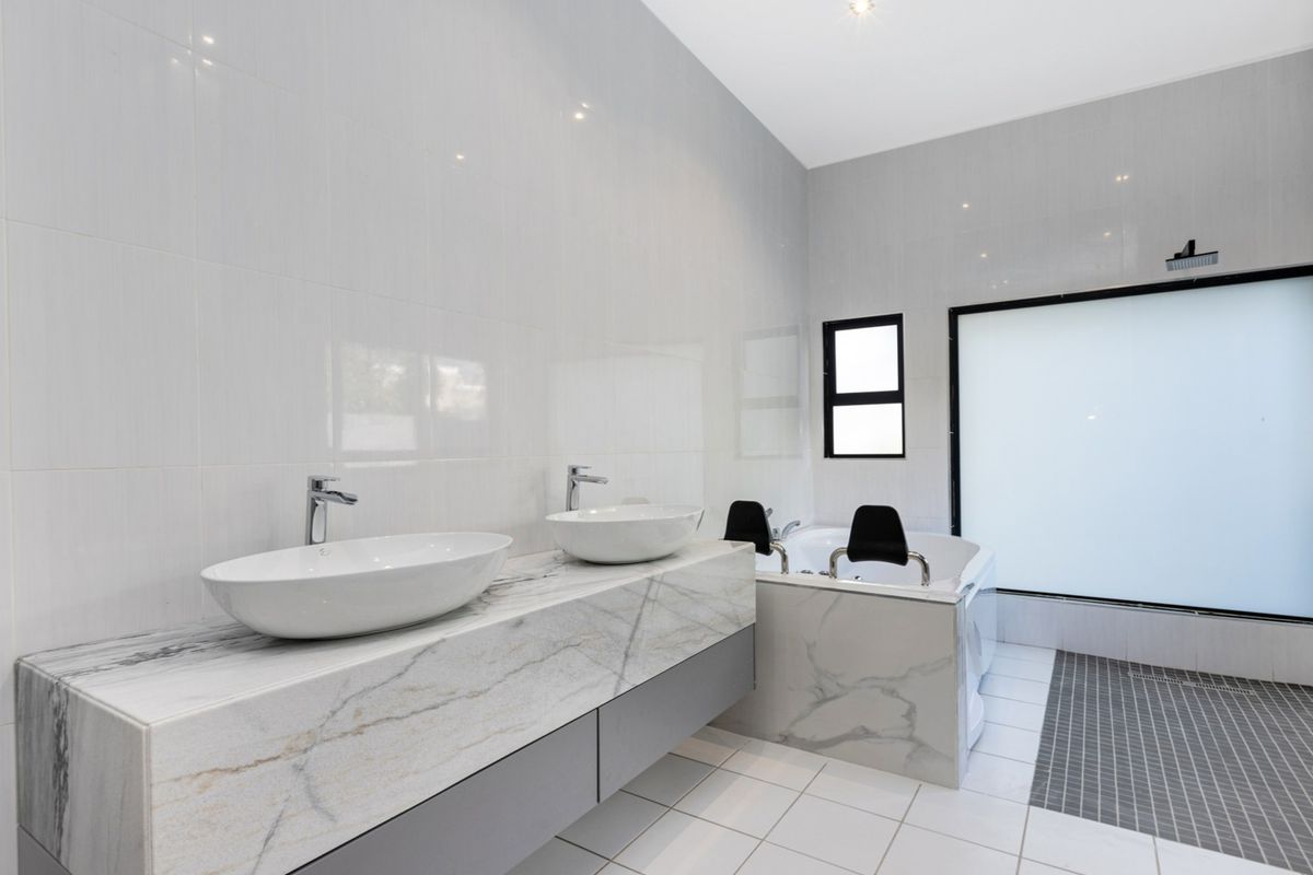 Modern bathroom featuring a floating marble-topped double vanity, a built-in soaking tub, and a walk-in shower area with contemporary tiling.