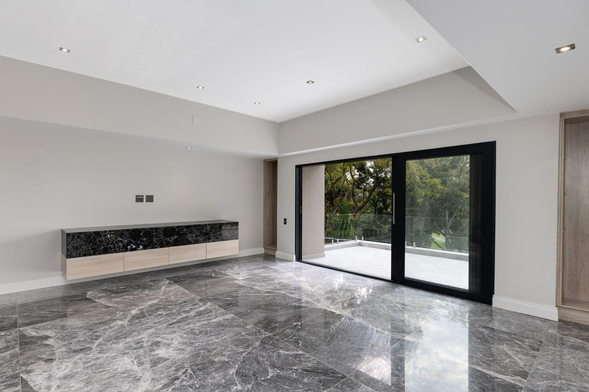 Spacious living area featuring polished marble flooring, recessed ceiling lighting, a built-in marble-topped media console, and large sliding glass doors opening to a balcony.