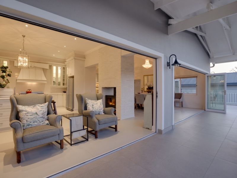 Spacious open-plan living area featuring a built-in fireplace, modern kitchen, and seamless transition to a covered patio through large stacking glass doors.