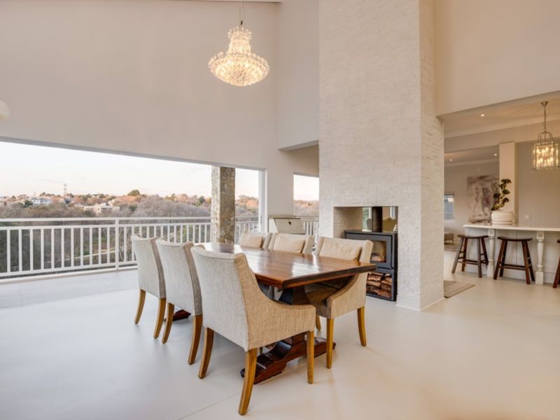 Spacious open-plan dining area featuring a striking stone-clad fireplace, vaulted ceilings, and seamless flow to an outdoor balcony with scenic views.