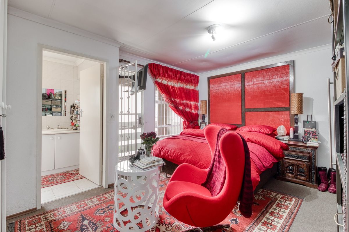 Spacious bedroom featuring a built-in headboard, direct access to an en-suite bathroom, and a security gate leading to an outdoor area.