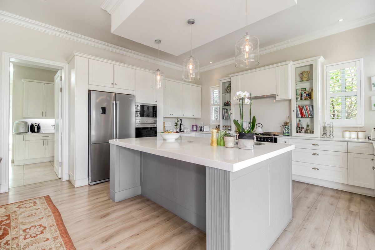 Modern kitchen featuring a central island with quartz countertops, white cabinetry, glass-front display units, and high-quality built-in appliances.