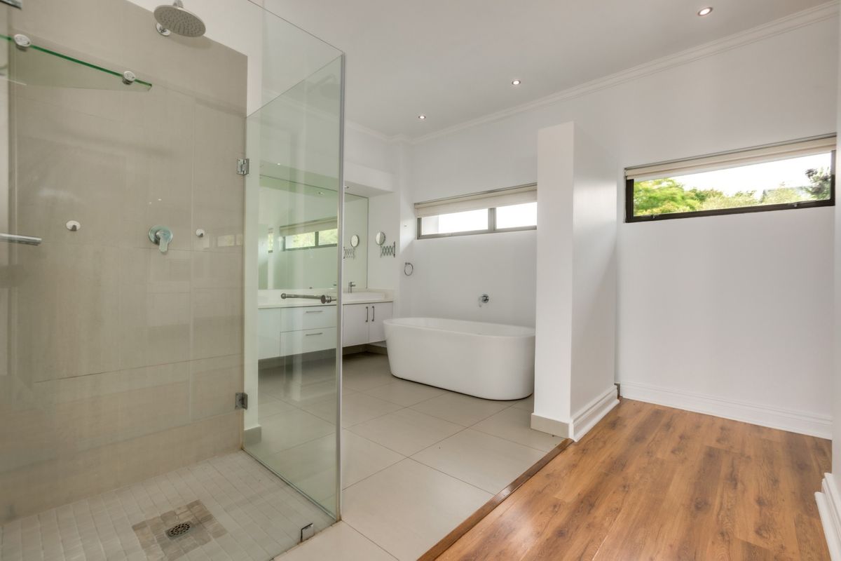 Modern bathroom featuring a glass-enclosed walk-in shower, a freestanding bathtub, and a double vanity with integrated storage.