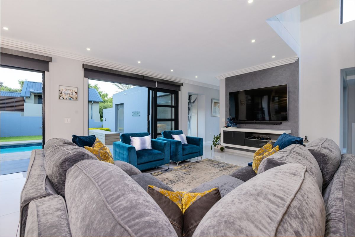 Modern living room featuring tiled floors, recessed lighting, a feature wall with built-in media console, and large sliding doors opening to the pool area.