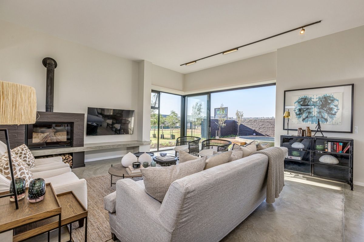 Modern living room featuring polished concrete floors, a built-in fireplace with concrete hearth, and large sliding glass doors opening to the garden.