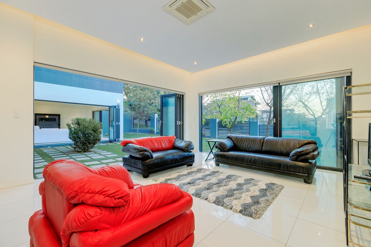 Spacious living room featuring large glass sliding doors that open onto a private garden, creating a seamless indoor-outdoor flow with modern recessed lighting.