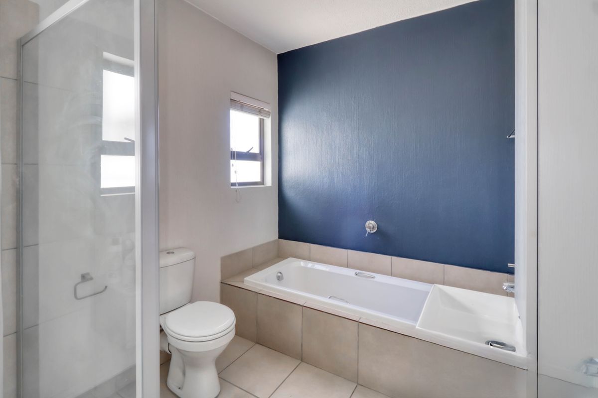 A clean bathroom featuring a built-in bathtub with tiled surround, a separate glass-enclosed shower, and a standard toilet.