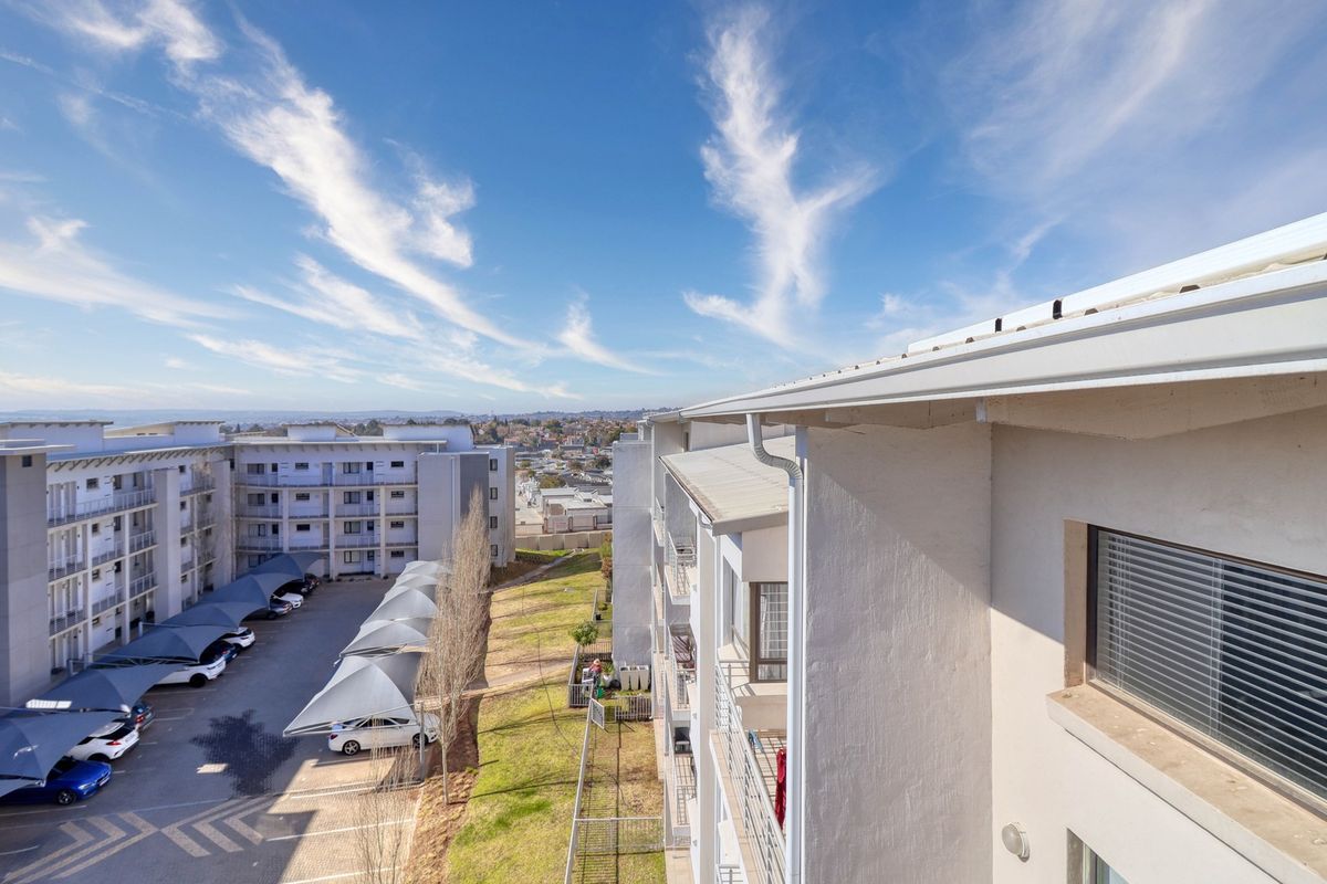Elevated view overlooking the townhouse complex, featuring paved parking areas with shade-cloth carports and surrounding residential infrastructure.