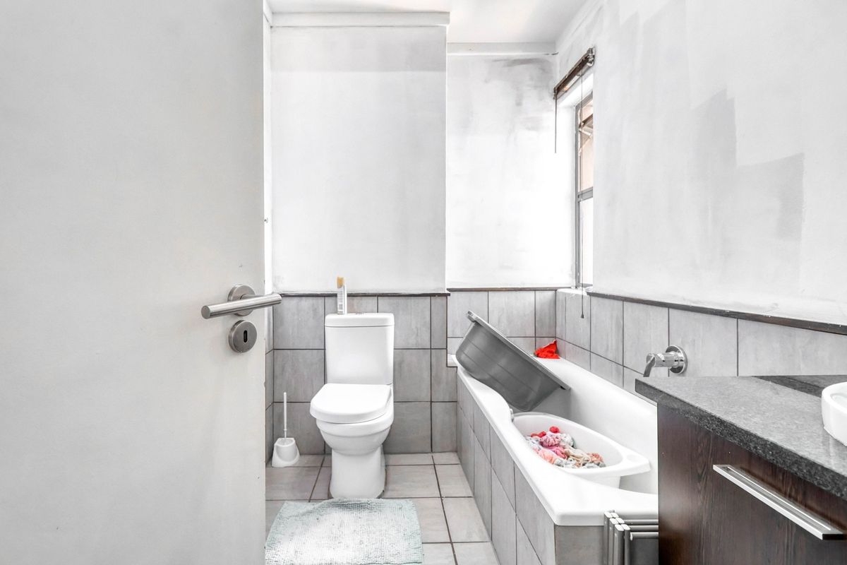 A compact bathroom featuring a bathtub, toilet, and vanity, currently requiring cosmetic attention to the wall finishes.