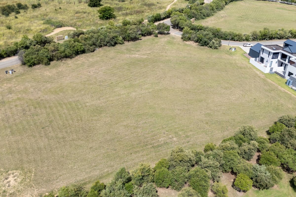 An aerial view of a vacant residential plot featuring established surrounding greenery and proximity to existing residential infrastructure.