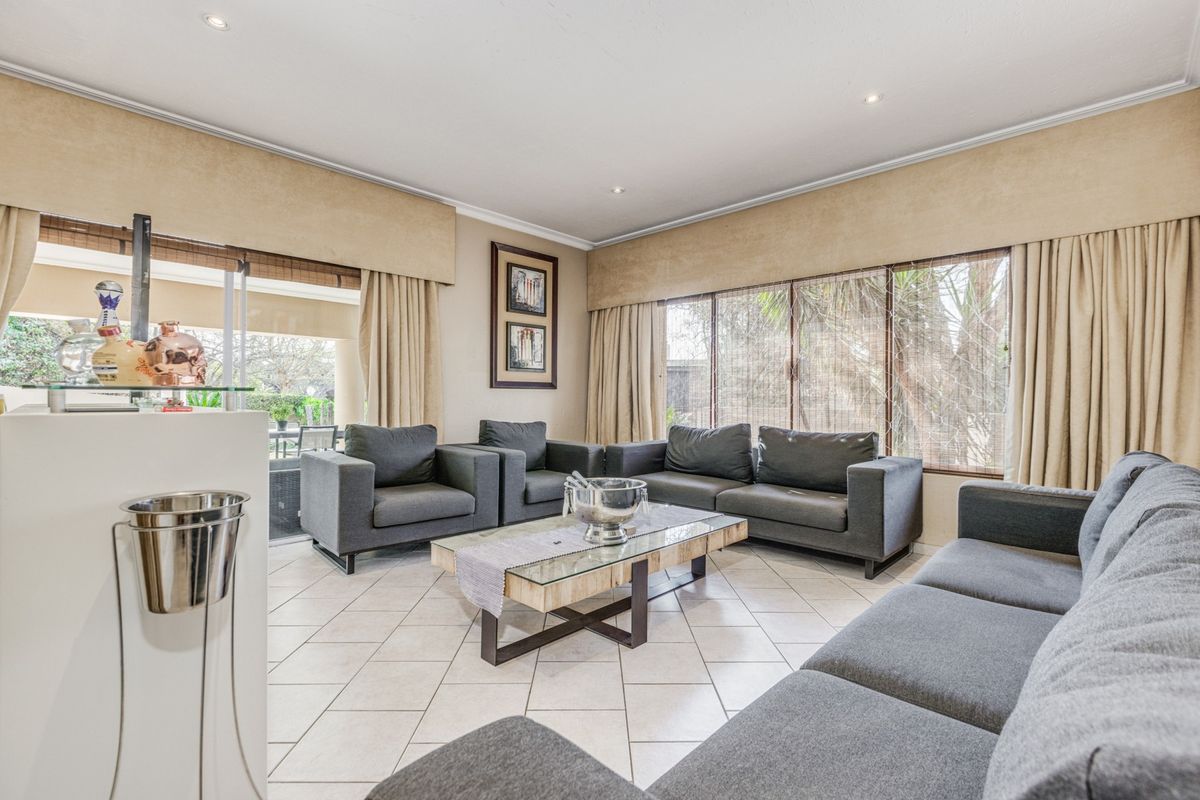 Spacious living room featuring large windows, tiled flooring, and recessed lighting, with direct access to an outdoor patio area.
