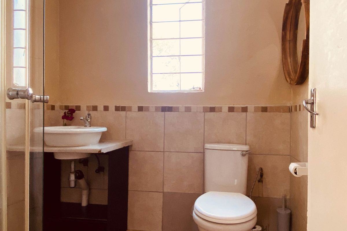 A functional bathroom featuring a ceramic basin, toilet, and tiled walls with a decorative border.