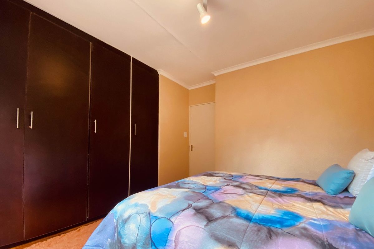 A bedroom featuring built-in dark wood cabinetry and neutral wall finishes, providing functional storage space.