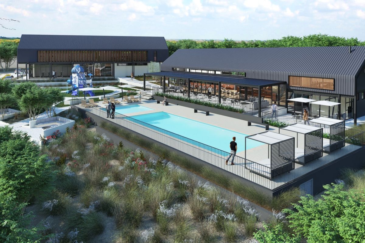 An aerial view of a modern residential development featuring a swimming pool, landscaped grounds, and contemporary buildings with metal roofing.