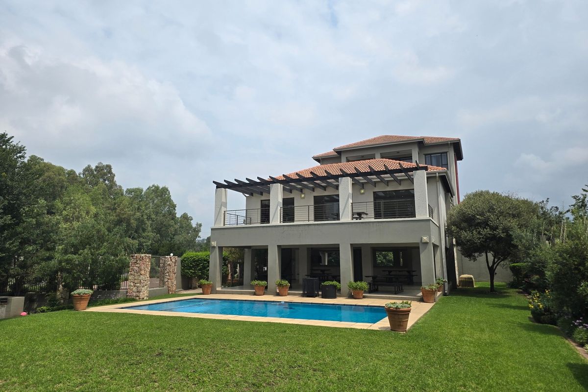 Rear view of a multi-story apartment building featuring a swimming pool, covered patio with pergola, and a well-maintained garden.