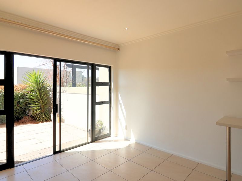 Bright and spacious living area featuring tiled floors, built-in shelving, and large sliding glass doors providing direct access to the outdoor patio area.